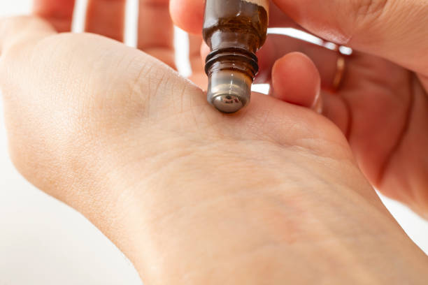 Woman rolling fragrance on her wrist.